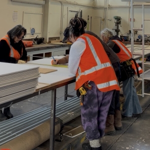 Three EIT carpentry students stand over a table with their tutor, as they learn carpentry at EIT Ruatōrea.